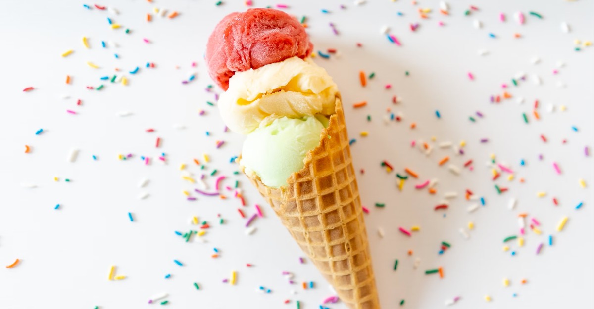 A photo of ice cream in a cone with sprinkles all over the table. (Photo: Courtney Cook / Unsplash)