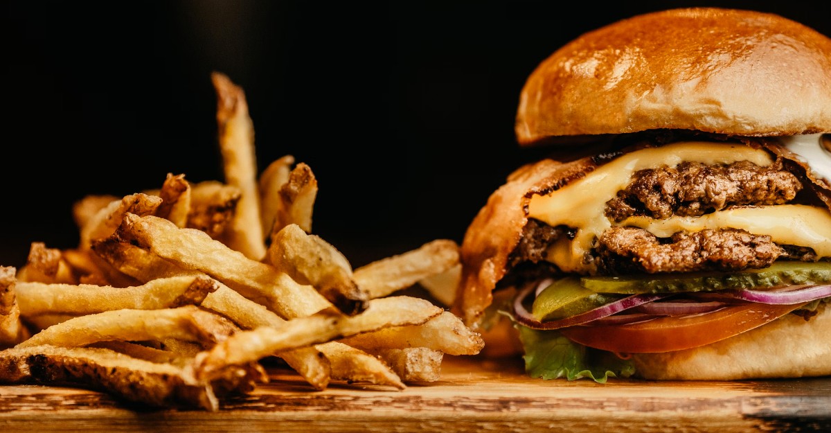 A photo of a burger and fries on a wooden table. (Photo: Jonathan Borba / Unsplash)