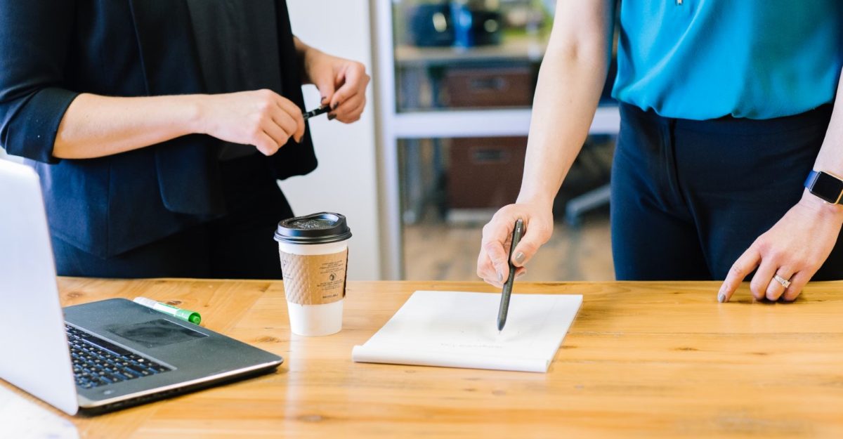 A photo of two workers looking at a piece of paper on a desk. (Photo: Amy Hirschi / Unsplash)