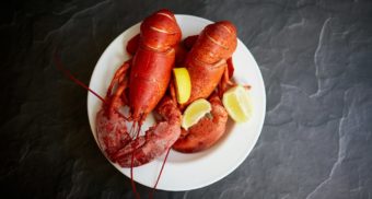 A lobster meal is served with a garnish of lemon.