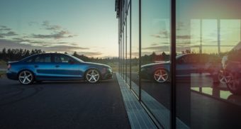 A blue car parked in front of glass windows, potentially at a car dealership in Canada.