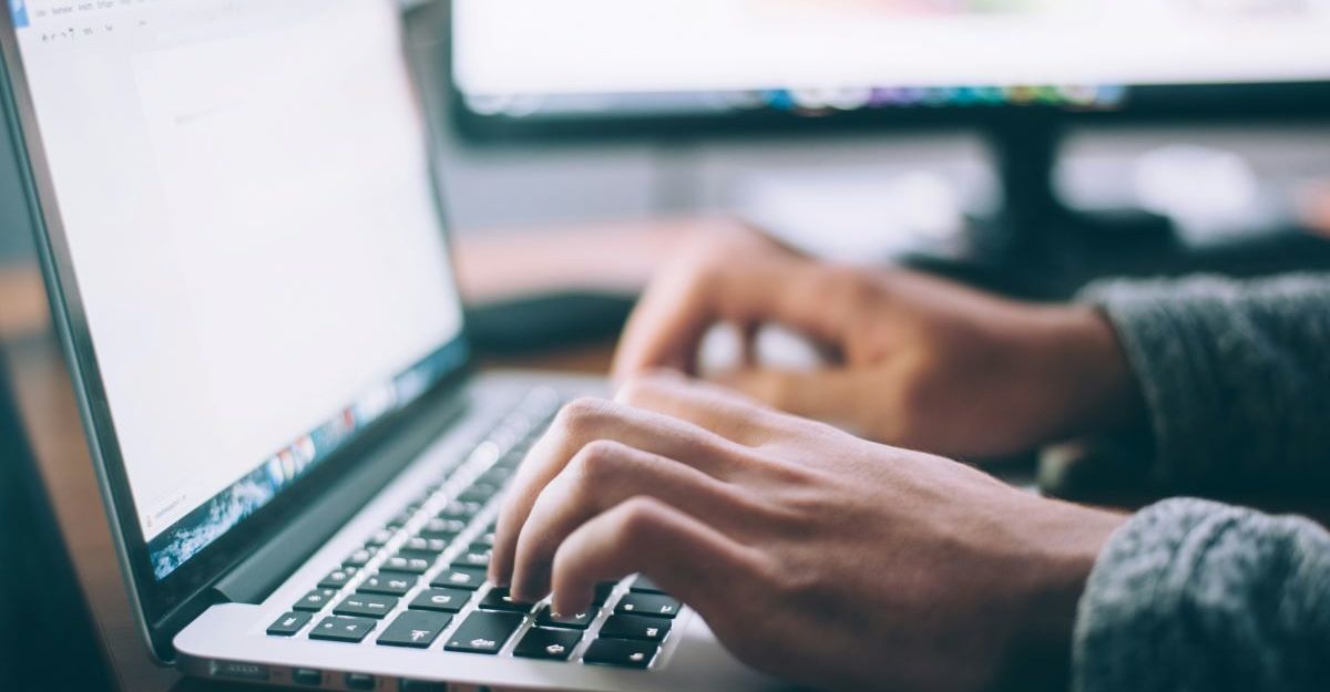 Someone's hands are seen using a laptop keyboard, potential operating software provided by GCG.