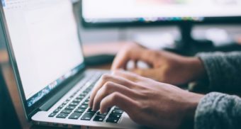 A close up of someone's hands hovering over a laptop keyboard, potentially working for HCL Canada.