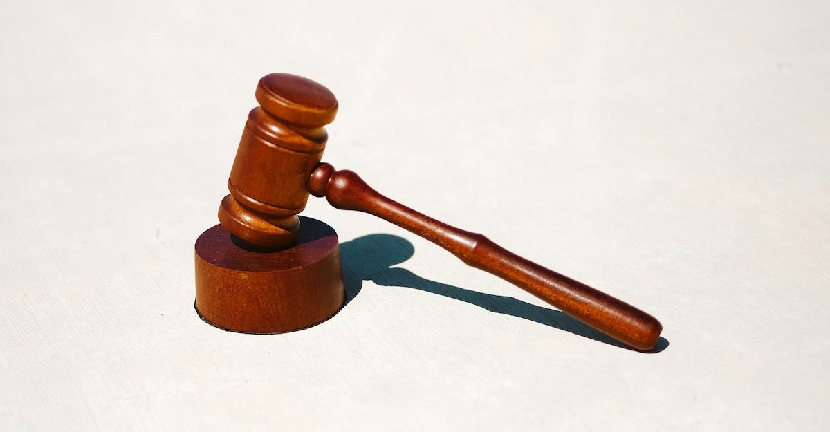 A gavel is featured against a grey background, used by a judge to pass judgement upon a lawyer's case.