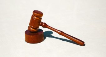 A gavel is featured against a grey background, used by a judge to pass judgement upon a lawyer's case.