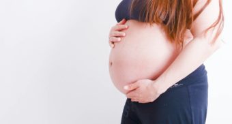 A woman clutches her pregnant belly.