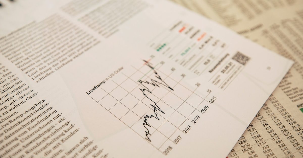 A sheet displaying financial information, possibly for Stifel Financial, sits on top of the stock section of a newspaper.