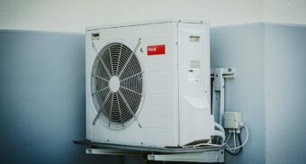 An air conditioning unit, potentially provided by a Carrier employee, is attached to a wall.