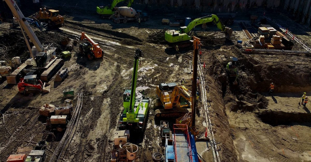 Multiple pieces of heavy equipment and numerous people are working at a construction site, potential operated by CRH Canada or one of its subsidiaries.