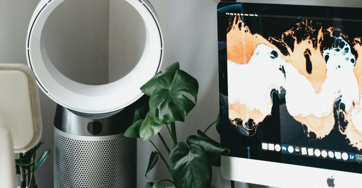 A bladless fan, similar to those made by Dyson Canada, sits next to a computer monitor.