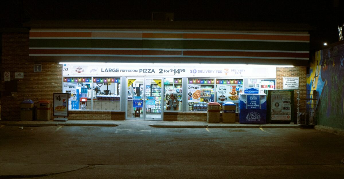 The front of a convenience store is lit up at night.