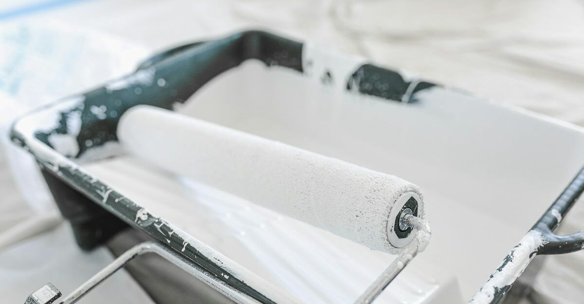 A paint roller sits on a tray which is potentially filled with Benjamin Moore paint.