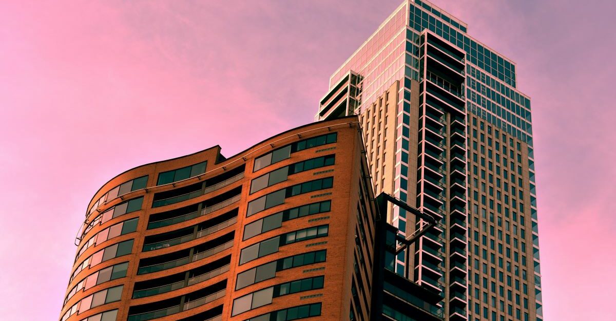 Two condo towers, potentially managed by Crossbridge, set against the purple hues of a sunset sky.