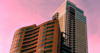 Two condo towers, potentially managed by Crossbridge, set against the purple hues of a sunset sky.