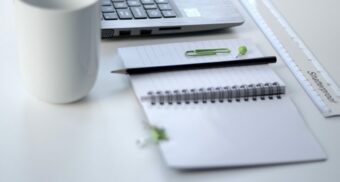 An open notebook sits next to a laptop.