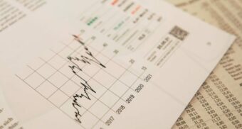 A sheet displaying financial information, possibly for Financeit, sits on top of the stock section of a newspaper.