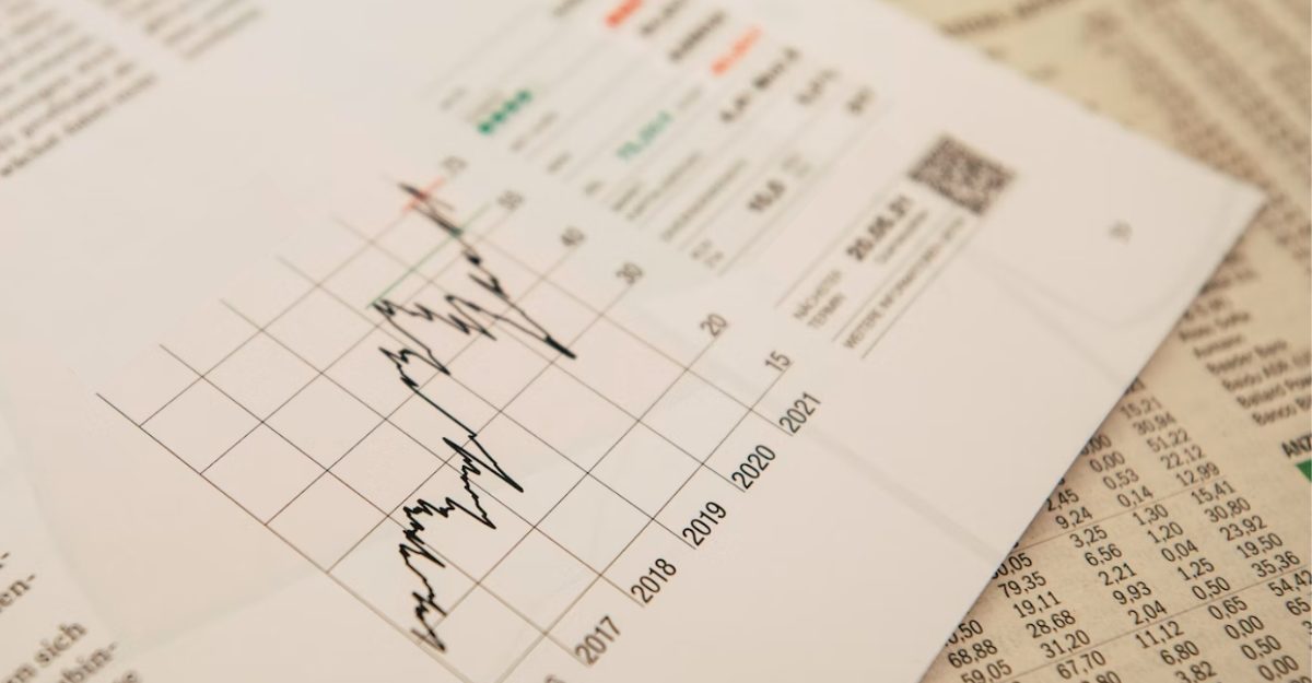 A sheet displaying financial information, possibly for Financeit, sits on top of the stock section of a newspaper.