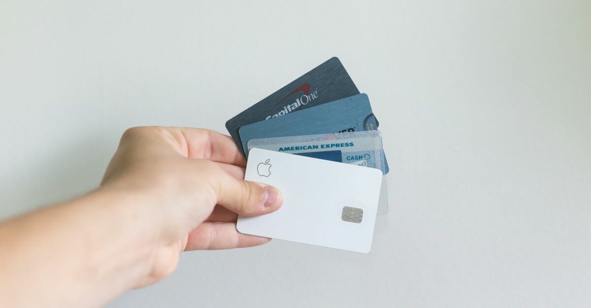 A hand clutching a number of credit cards, potentially including a Mastercard.