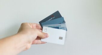 A hand clutching a number of credit cards, potentially including a Mastercard.