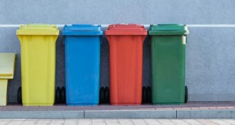 Multicoloured garbage bins are lined up, waiting to be emptied by Waste Connections of Canada.