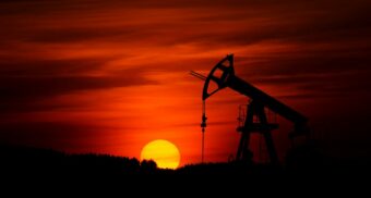 A pump-jack operating against the backdrop of the setting sun.