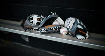 Baseball gloves and balls are seen on a bench.