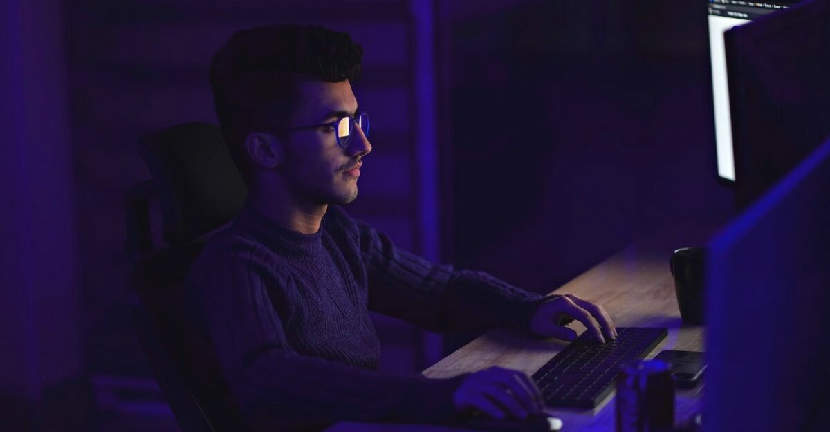 A photo of a person looking at multiple computer screens. (Photo: Mohammad Rahmani / Unsplash)