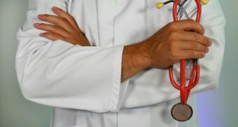 A doctor, potentially working at a Halton Healthcare hospital, holds a stethoscope.