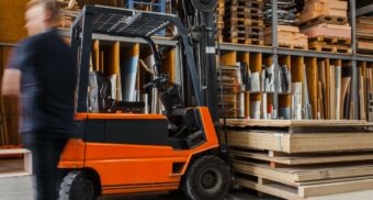 A photo of a person walking past a forklift in a warehouse (Photo: Pickawood / Unsplash)