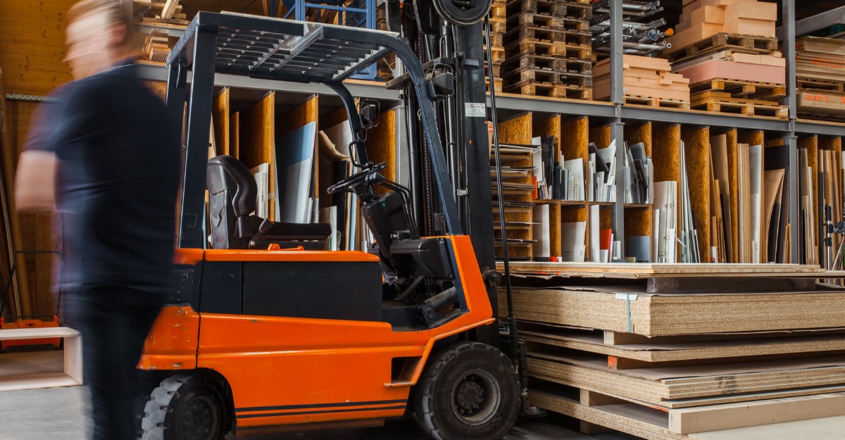 A photo of a person walking past a forklift in a warehouse (Photo: Pickawood / Unsplash)