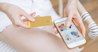 A woman makes an online payment with her smartphone, potentially facilitated by Interac.