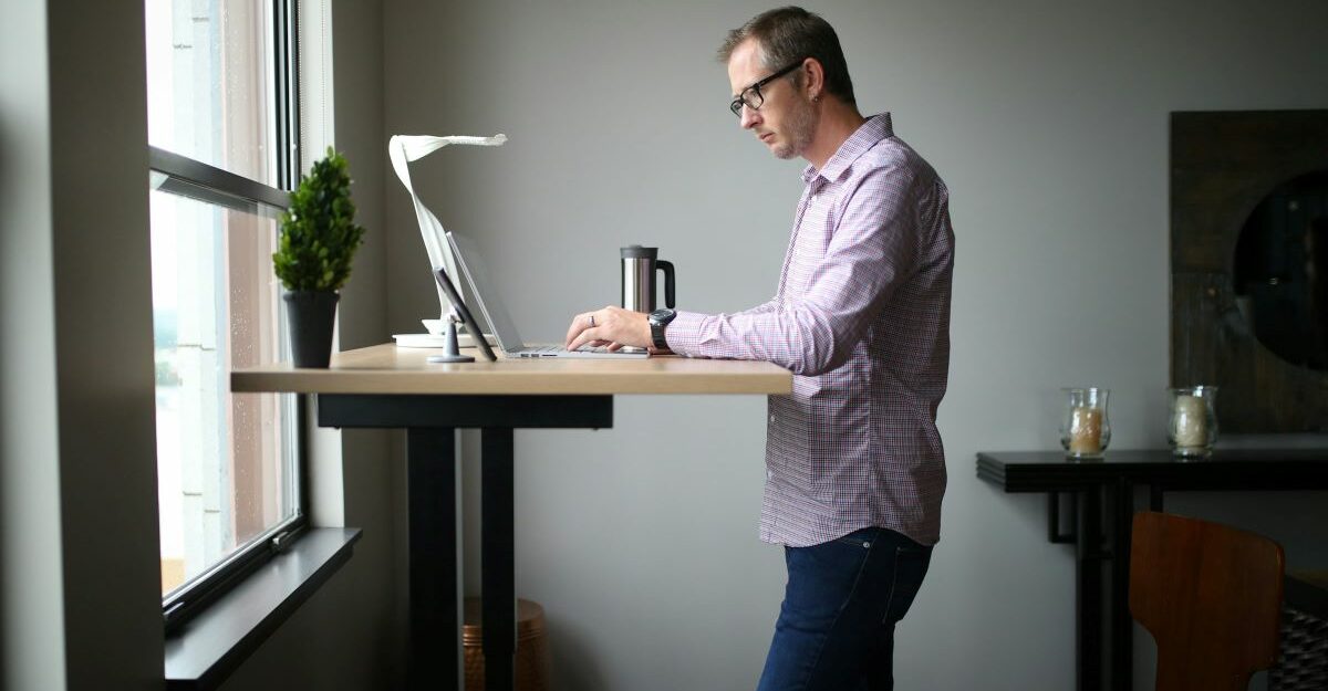 An employee uses the computer on their standing desk at work.