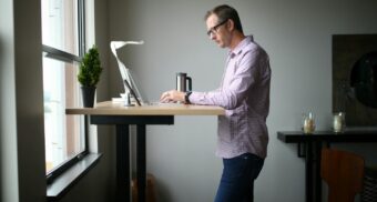 An employee uses the computer on their standing desk at work.