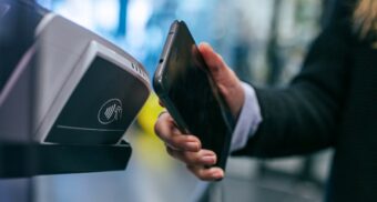 A photo of a person using an app on their phone at a contactless payment terminal. (Photo: Jonas Leupe / Unsplash)