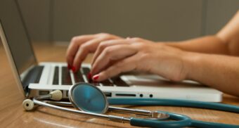 A doctor reviews a patient's medical conditions on a laptop.