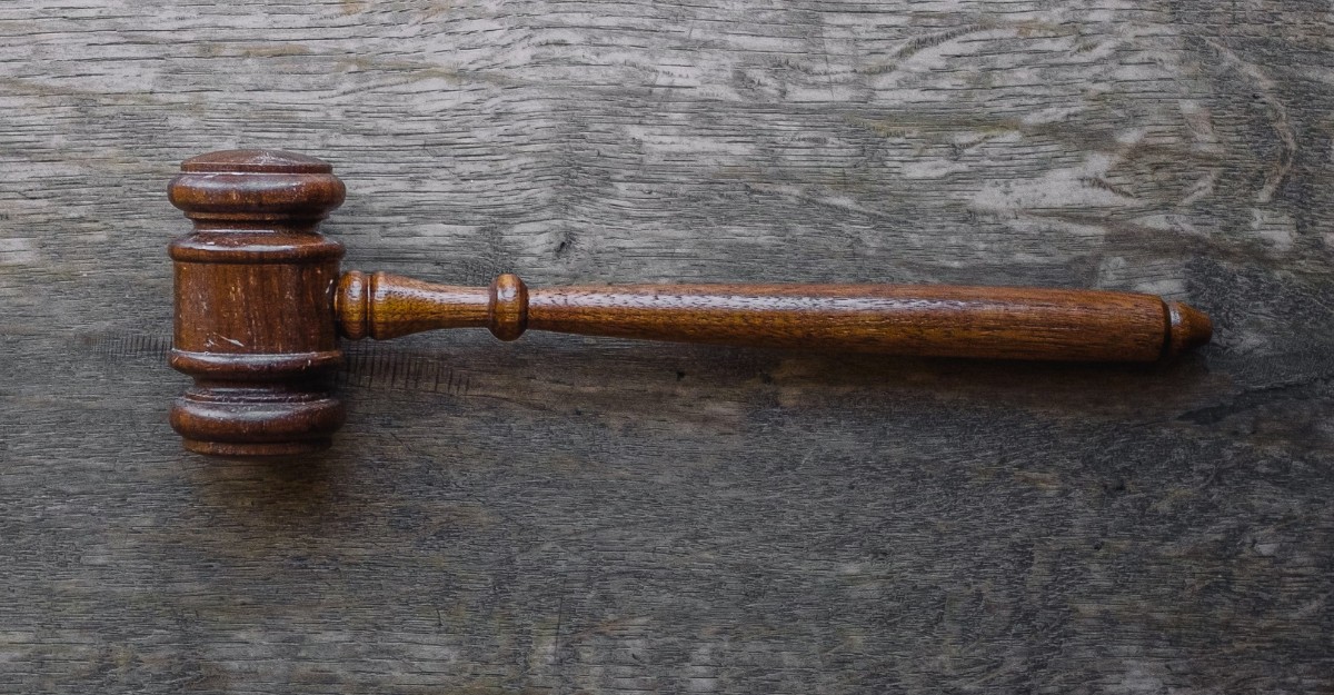 A photo of a brown gavel on a wooden table. (Photo: Wesley Tingey / Unsplash)