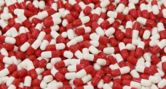 A large quantity of red and white pills on a table. (Photo: Analuisa Gamboa / Unsplash)