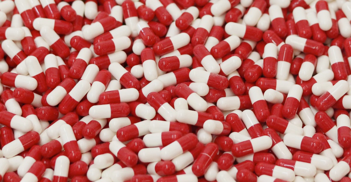 A large quantity of red and white pills on a table. (Photo: Analuisa Gamboa / Unsplash)