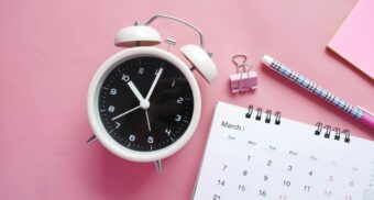 An alarm clock sits next to a calendar.