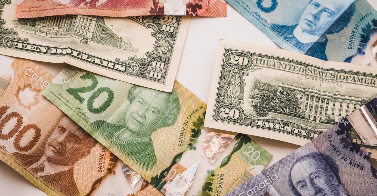 A photo of Canadian and American money on a table. (Photo: PiggyBank / Unsplash)