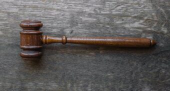 A photo of a brown gavel on a wooden table. (Photo: Wesley Tingey / Unsplash)