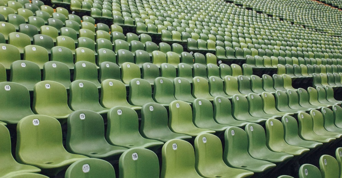 A photo of green chairs with numbers on them in a stadium. (Photo: Markus Spiske / Unsplash)