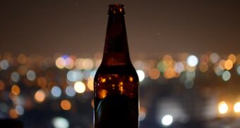 A photo of a beer bottle outside at night. (Photo: Eeshan Garg / Unsplash)