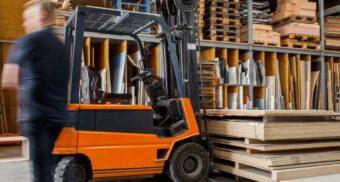 A photo of a person walking past a forklift in a warehouse (Photo: Pickawood / Unsplash)