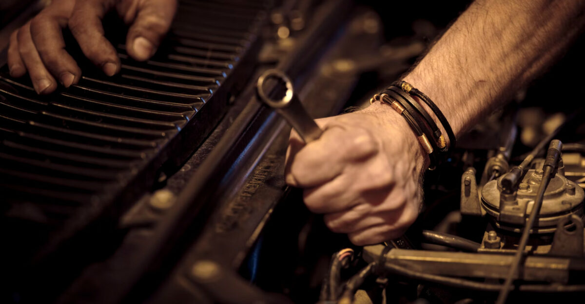 An auto worker uses tools on a vehicle's engine. (Photo: Christian Buehner / Unsplash)