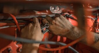 A photo of a mechanic working on a piece of machinery. (Photo: Nina Mercado / Unsplash)