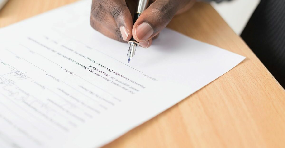at-will-employment-canada A hand is seen signing an employment contract.