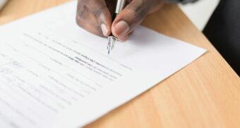 A hand is seen signing an employment contract.