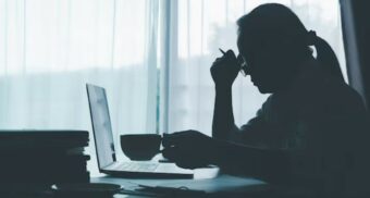 A photo of a person rubbing their forehead while staring at a laptop. (Photo: dapor2560 / Freepik)