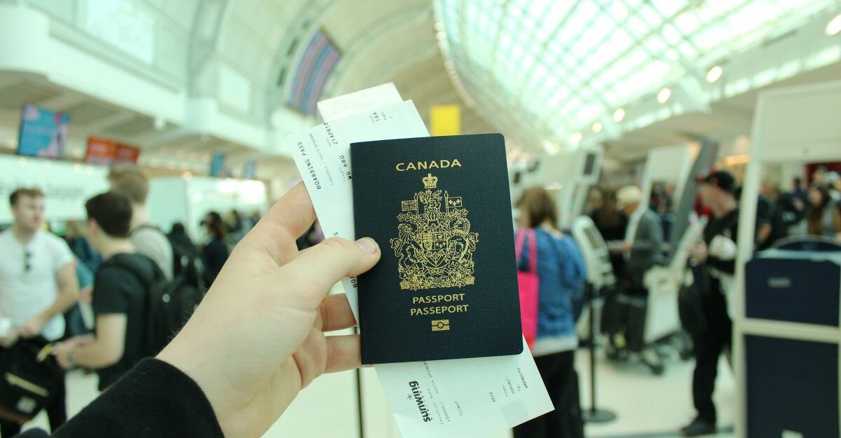 An air traveller holds a Canadian passport in their hand.